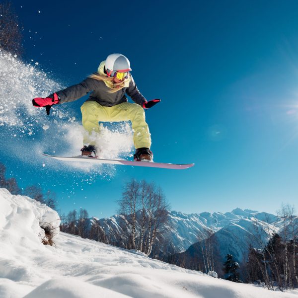 Girl is jumping with snowboard from the hill
